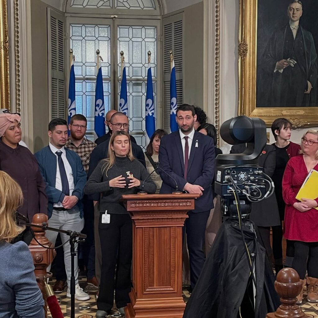 Des membres de la communauté immigrante accompagnée du député Guillaume Cliche-Rivard devant l'Assemblée nationale du Québec, le 26 novembre 2025 (Source : Le Québec c'est nous aussi)